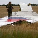 Armed pro-Russian separatist stands on part of the wreckage of the Malaysia Airlines Boeing 777 plane after it crashed near the settlement of Grabovo in the Donetsk region