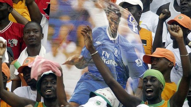 Jubilant Ivory Coast fans hold up a poster of Didier Drogba in Chelsea kit