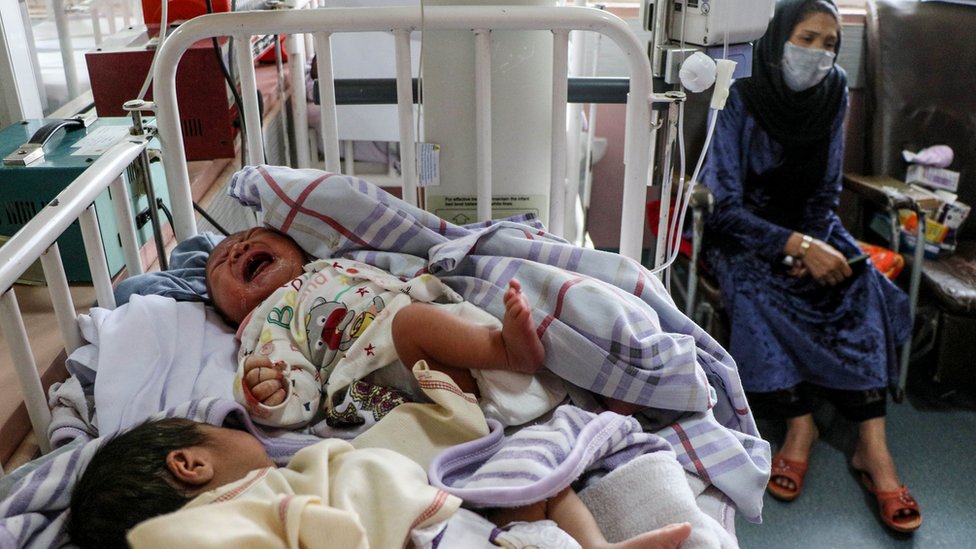 A woman sits next to new-born babies who lost their mothers following a suicide attack on a maternity hospital in Afghanistan