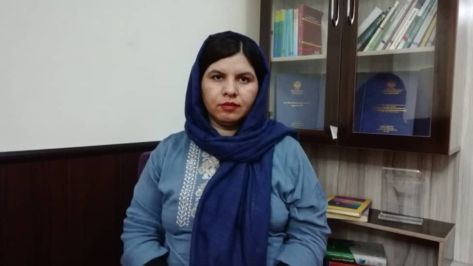 Firooza Omar in front of a cupboard holding books