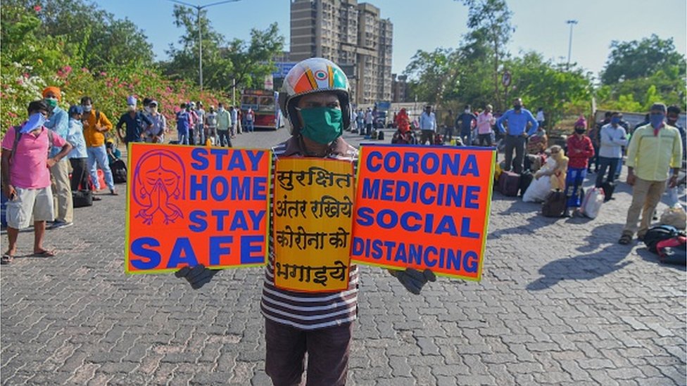 Social worker Surender holds placards to create awareness about social distancing in Mumbai on May 11, 2020