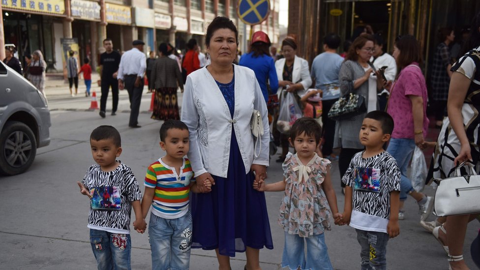 This file photo taken on June 4, 2019 shows a Uighur woman waiting with children on a street in Kashgar in China"s northwest Xinjiang region.