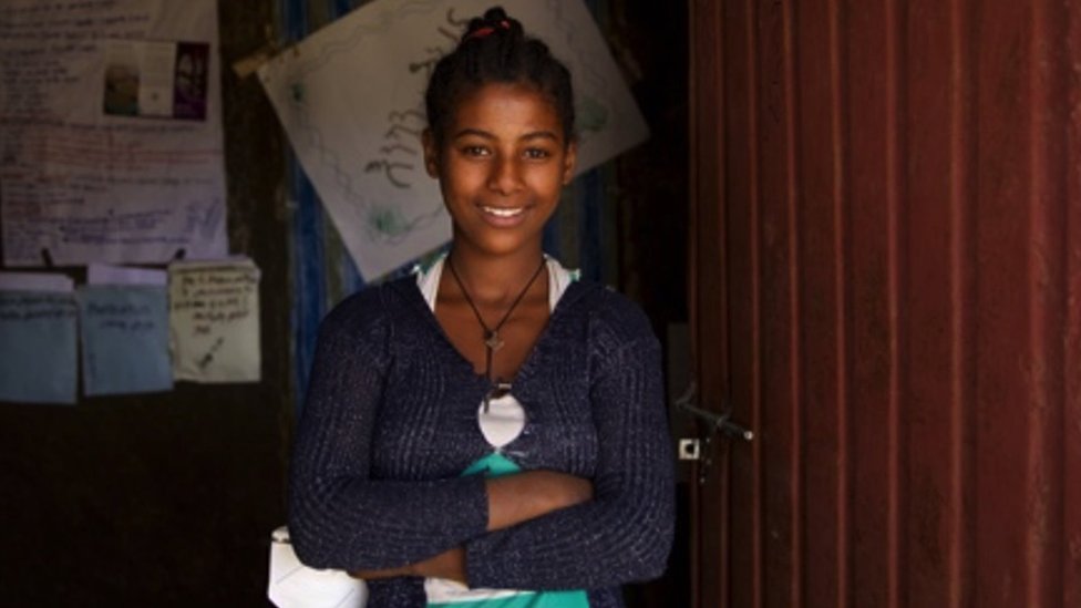 Abeba stands by her school's doors