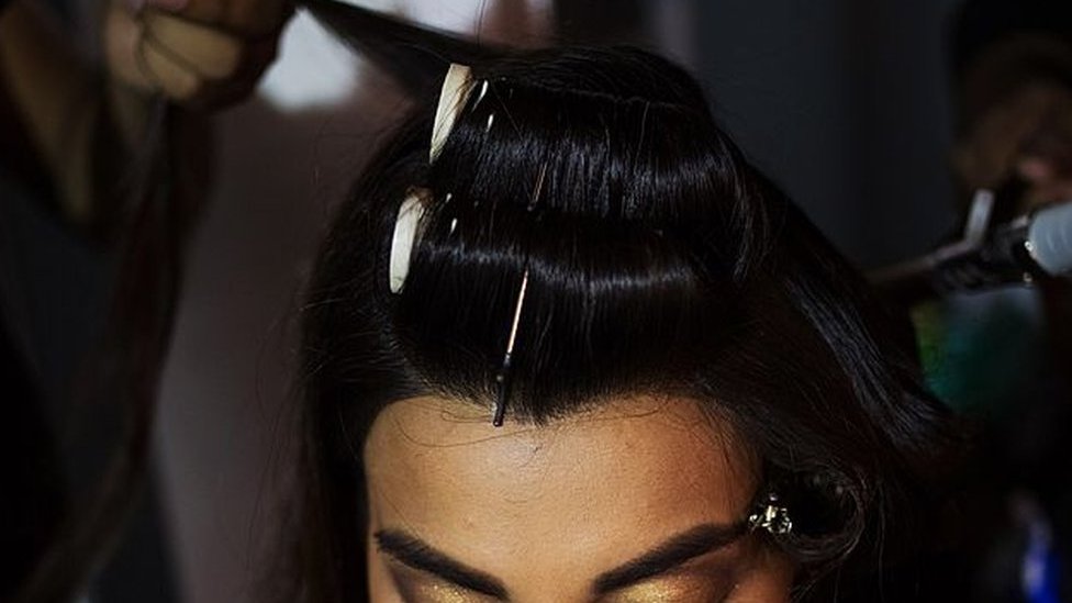 An Indian model sits as she has her hair styled backstage ahead of the Ashima Leena fashion show at Bridal Fashion Week in New Delhi.